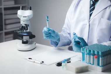 Laboratuvar asistanı, tıp bilimcisi, kimya araştırmacısı kimyasal test tüpünden cam bir tüp tutuyor, kimyasal deney yapıyor ve hastanın örneğini inceliyor. Tıp ve araştırma konsepti.