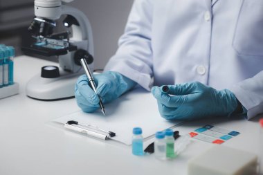 Laboratuvar asistanı, tıp bilimcisi, kimya araştırmacısı kimyasal test tüpünden cam bir tüp tutuyor, kimyasal deney yapıyor ve hastanın örneğini inceliyor. Tıp ve araştırma konsepti.