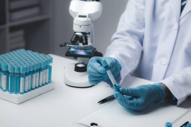 Laboratuvar asistanı, tıp bilimcisi, kimya araştırmacısı kimyasal test tüpünden cam bir tüp tutuyor, kimyasal deney yapıyor ve hastanın örneğini inceliyor. Tıp ve araştırma konsepti.