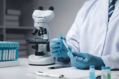 Laboratuvar asistanı, tıp bilimcisi, kimya araştırmacısı kimyasal test tüpünden cam bir tüp tutuyor, kimyasal deney yapıyor ve hastanın örneğini inceliyor. Tıp ve araştırma konsepti.
