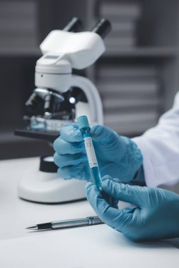 Laboratuvar asistanı, tıp bilimcisi, kimya araştırmacısı kimyasal test tüpünden cam bir tüp tutuyor, kimyasal deney yapıyor ve hastanın örneğini inceliyor. Tıp ve araştırma konsepti.