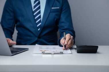 İşadamı şirketinde özel bir ofiste oturuyor ve şirketin mali belgelerini inceliyor, üst düzey yönetim finansal bilgilerin doğruluğunu kontrol ediyor. Mali yönetim.