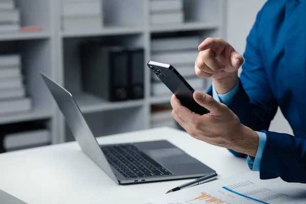 stock image Business man looking at financial information from a mobile phone, he is checking company financial documents, he is an executive of a startup company. Concept of financial management.