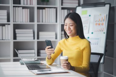 Genç bir kadın girişimci bir işkadınıdır, ofiste oturur ve cep telefonu kullanır, işlerini genç bir nesilden yönetir ve yönetir. Girişim işletme yönetimi kavramı.