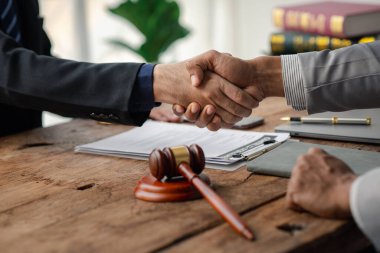 Avukatlar, bu işe ortak yatırım yapan iş ortaklarının zimmetine para geçirme davasında tanıklık etmeye gelen müşterilerle tokalaşıyorlar. Yasal işlemler için avukat tutma kavramı.