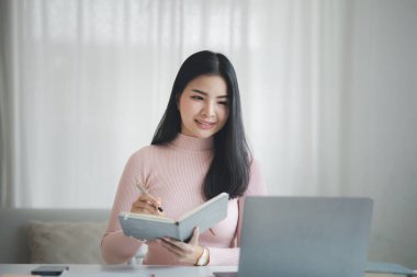 A beautiful Asian businesswoman sitting in her private office, she is checking company financial documents, she is a female executive of a startup company. Concept of financial management.