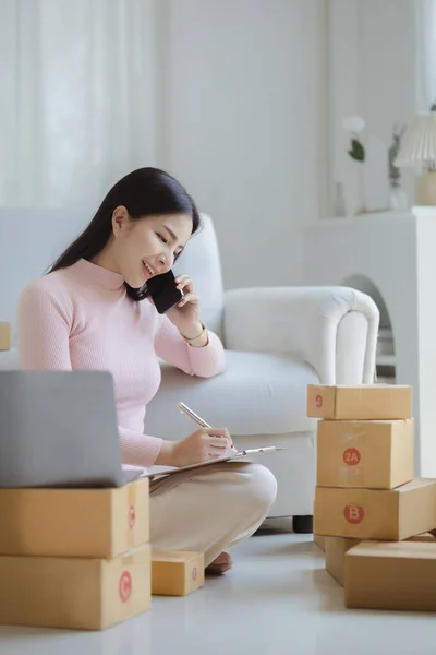Selling products online, Young Asian store owner talking on the phone, she does online selling, live selling on social media platforms to reach target audience. Concept of selling products online.