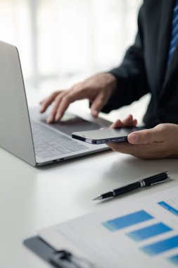Business man looking at financial information from a mobile phone, he is checking company financial documents, he is an executive of a startup company. Concept of financial management.