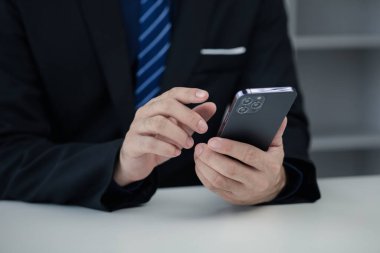 Business man looking at financial information from a mobile phone, he is checking company financial documents, he is an executive of a startup company. Concept of financial management.