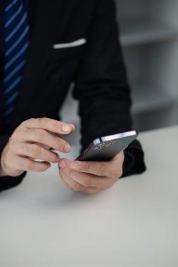 Business man looking at financial information from a mobile phone, he is checking company financial documents, he is an executive of a startup company. Concept of financial management.