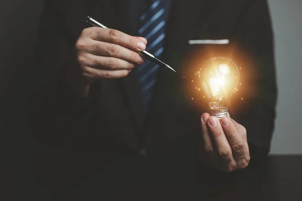 stock image Businessman holding glowing lamp, Creative new idea. Innovation, brainstorming, strategizing to make the business grow and be profitable. Concept execution, strategy planning and profit management.