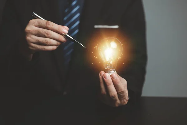 Businessman holding glowing lamp, Creative new idea. Innovation, brainstorming, strategizing to make the business grow and be profitable. Concept execution, strategy planning and profit management.