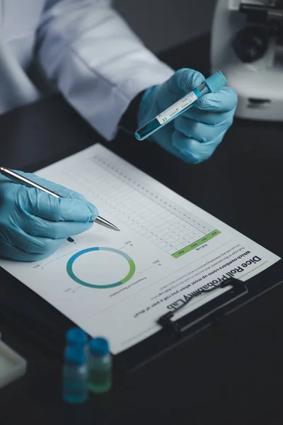 stock image Lab assistant, medical scientist, chemistry researcher holds a glass tube through a chemical test tube, does a chemical experiment and examines a patient's sample. Medicine and research concept.