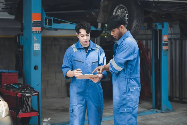 Dwóch Zawodowych Mechaników Samochodów Patrząc Dokumenty Kontroli Samochodu Razem Wszystkie — Zdjęcie stockowe
