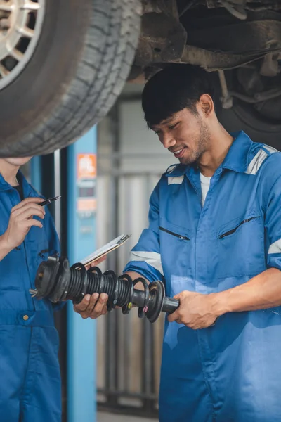 Two professional car mechanics helping to repair shock absorbers and car suspension, all kinds of car experts, expert auto repair and accredited auto repair center.