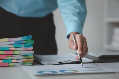 Bir finans uzmanı, finans departmanı tarafından iş ortaklarıyla yapılacak bir toplantı için hazırlanan finansal belgeleri inceliyor. Mali rakamların doğruluğunu doğrulama kavramı.