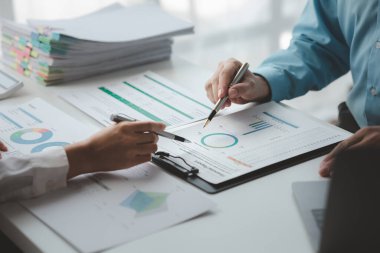 Businessman is reviewing monthly sales documents for analysis and marketing plans for more sales growth, they are the founders of young companies co-founding startups. Sales management concept.