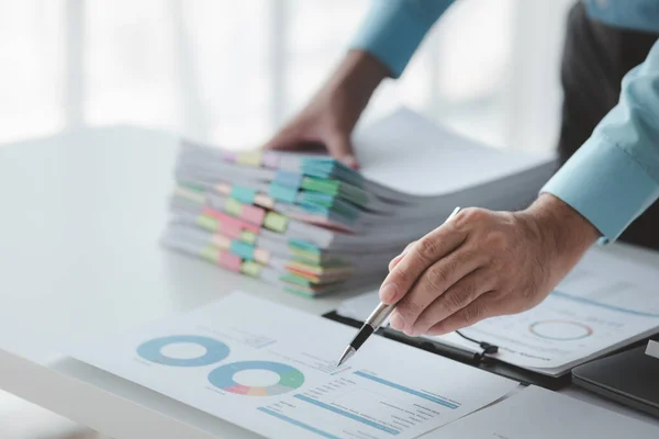 A business finance man is reviewing a company\'s financial documents prepared by the Finance Department for a meeting with business partners. Concept of validating the accuracy of financial numbers.
