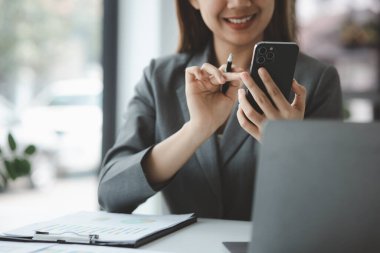 Cep telefonu tutan ve internette sörf yapan, akıllı telefondaki uygulamaları çalıştıran, e-postaları cevaplayan ve iş arkadaşlarıyla mesajlaşan bir kadın. İletişim için teknolojiyi kullanma kavramı.