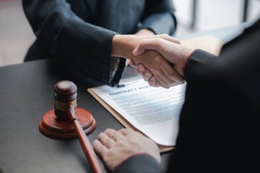 Avukatlar, bu işe ortak yatırım yapan iş ortaklarının zimmetine para geçirme davasında tanıklık etmeye gelen müşterilerle tokalaşıyorlar. Yasal işlemler için avukat tutma kavramı.