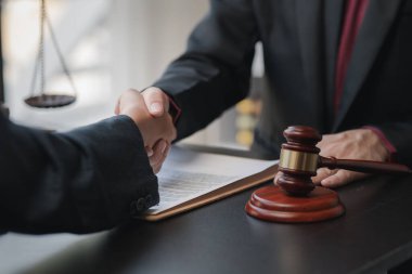 Avukatlar, bu işe ortak yatırım yapan iş ortaklarının zimmetine para geçirme davasında tanıklık etmeye gelen müşterilerle tokalaşıyorlar. Yasal işlemler için avukat tutma kavramı.
