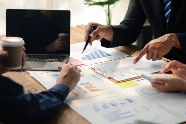 Grup işadamları, ortak iş sorunlarını geliştirmek ve çözmek için birlikte çalışarak toplantının materyallerine işaret ediyorlar. Büyüme ve kalite için işletme yönetimi kavramı.