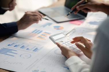 Grup işadamları, ortak iş sorunlarını geliştirmek ve çözmek için birlikte çalışarak toplantının materyallerine işaret ediyorlar. Büyüme ve kalite için işletme yönetimi kavramı.