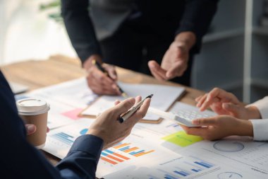 Grup işadamları, ortak iş sorunlarını geliştirmek ve çözmek için birlikte çalışarak toplantının materyallerine işaret ediyorlar. Büyüme ve kalite için işletme yönetimi kavramı.