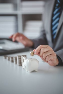 Person with pile of coins and piggy bank, money saving concept for future use and financial stability, salary management, personal finance, investment savings.