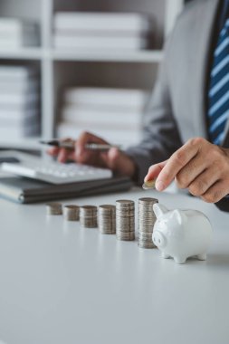 Person with pile of coins and piggy bank, money saving concept for future use and financial stability, salary management, personal finance, investment savings.