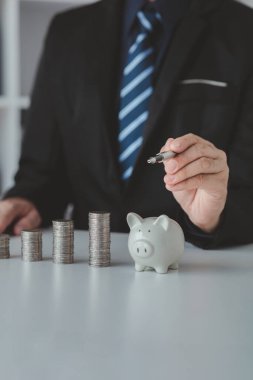 Person with pile of coins and piggy bank, money saving concept for future use and financial stability, salary management, personal finance, investment savings.