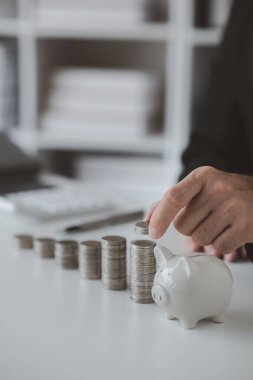 Person with pile of coins and piggy bank, money saving concept for future use and financial stability, salary management, personal finance, investment savings.