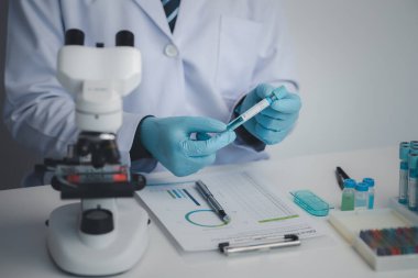 Laboratuvar asistanı, tıp bilimcisi, kimya araştırmacısı kimyasal test tüpünden cam bir tüp tutuyor, kimyasal deney yapıyor ve hastanın örneğini inceliyor. Tıp ve araştırma konsepti.