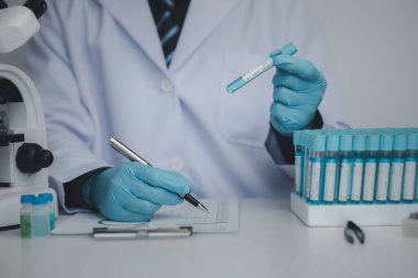 Laboratuvar asistanı, tıp bilimcisi, kimya araştırmacısı kimyasal test tüpünden cam bir tüp tutuyor, kimyasal deney yapıyor ve hastanın örneğini inceliyor. Tıp ve araştırma konsepti.