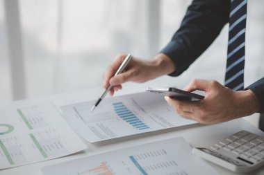 Şirketindeki özel bir ofiste iş adamı ve şirketin mali belgelerini inceliyor, üst düzey yönetim finansal bilgilerin doğruluğunu kontrol ediyor. Mali yönetim.