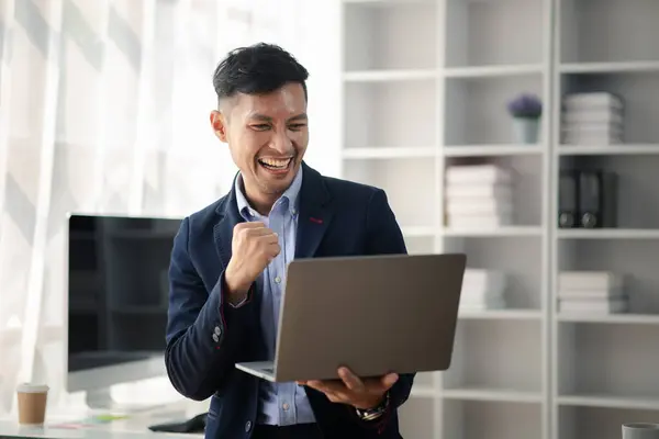 stock image Man holding laptop and celebrating, he is young energetic businessman, modern business management, start-up company run by young people, modern entrepreneur with fresh ideas. to be a business leader.