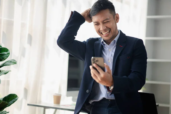 Man holding mobile phone and celebrating, he is young businessman, modern business management, start-up company run by young people, modern entrepreneur with new ideas. to be a business leader.