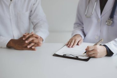 Doktor ve hasta tedavinin detaylarını, hastanın fiziksel muayenesinin sonuçlarını tartışıyorlar. Yıllık fiziksel muayene kavramı.