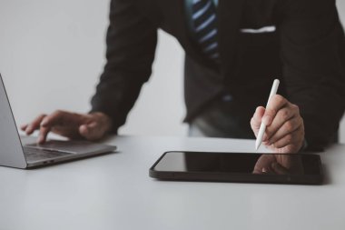 Tabletli bir işadamı, iş belgelerine bakmak ve internet üzerinden e-posta göndererek iletişim kurmak için tableti kullanıyor. İletişim için teknolojiyi kullanma kavramı.