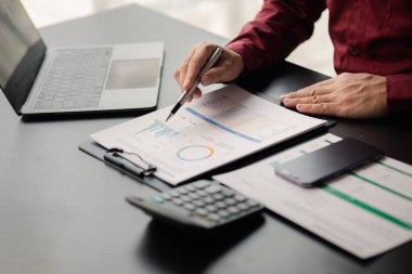 Business man checking financial documents, he owns a startup company, he sits checking the company's financial summary prepared by the finance department. Management concept of startup company.	