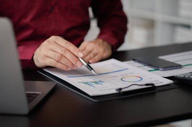 Business man checking financial documents, he owns a startup company, he sits checking the company's financial summary prepared by the finance department. Management concept of startup company.	
