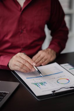 Business man checking financial documents, he owns a startup company, he sits checking the company's financial summary prepared by the finance department. Management concept of startup company.	