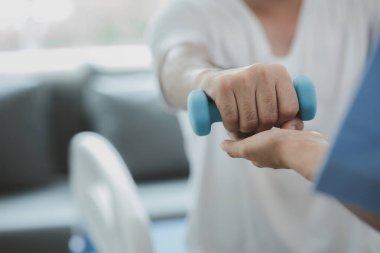 Hastane odasında bir hasta için fizyoterapi yapan bir fizyoterapist, vücudu ve kasları hareket ettirerek hastalıktan kurtulmaya yardımcı olur. Hastalıkları fizik tedaviyle tedavi etme kavramı..