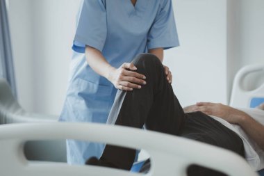 Profesyonel bir fizyoterapist hastanın bacaklarını esnetiyor, çok çalışmaktan dolayı kas bozukluğu yaşıyor, çoğu zaman uzun süre oturma sorunu olan bir ofis çalışanı..