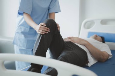 Profesyonel bir fizyoterapist hastanın bacaklarını esnetiyor, çok çalışmaktan dolayı kas bozukluğu yaşıyor, çoğu zaman uzun süre oturma sorunu olan bir ofis çalışanı..