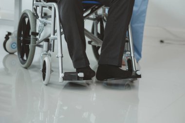 Tekerlekli sandalyede oturan erkek hasta uzman doktorla birlikte tıbbi muayeneye tabi tutuluyor, yaraları tedavi ediliyor uzman doktordan doğru ve düzgün bir tedavi görüyor.