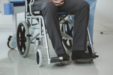 Tekerlekli sandalyede oturan erkek hasta uzman doktorla birlikte tıbbi muayeneye tabi tutuluyor, yaraları tedavi ediliyor uzman doktordan doğru ve düzgün bir tedavi görüyor.