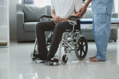 Tekerlekli sandalyede oturan erkek hasta uzman doktorla birlikte tıbbi muayeneye tabi tutuluyor, yaraları tedavi ediliyor uzman doktordan doğru ve düzgün bir tedavi görüyor.