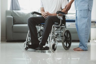 Tekerlekli sandalyede oturan erkek hasta uzman doktorla birlikte tıbbi muayeneye tabi tutuluyor, yaraları tedavi ediliyor uzman doktordan doğru ve düzgün bir tedavi görüyor.