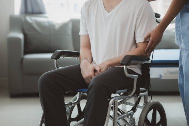 Tekerlekli sandalyede oturan erkek hasta uzman doktorla birlikte tıbbi muayeneye tabi tutuluyor, yaraları tedavi ediliyor uzman doktordan doğru ve düzgün bir tedavi görüyor.